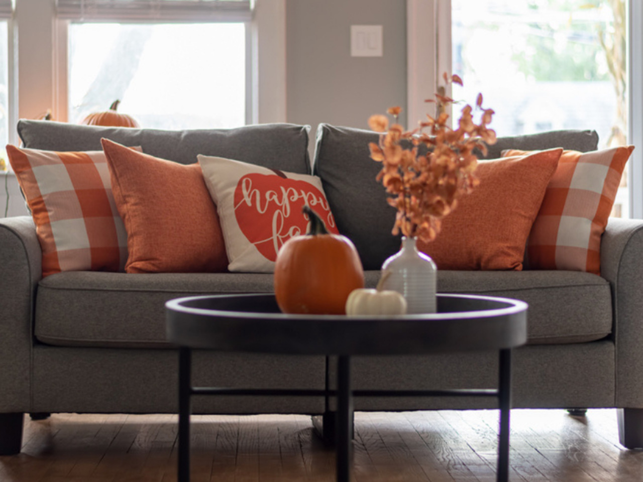 Cozy living room scene featuring a gray couch, fall-colored pillows, and a floral centerpiece - eastdouglasinsurance.com